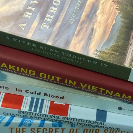 A stack of books. Titles include: A River Runs Through It; Speaking Out in Vietnam; In Cold Blood; Institutions, , Institutional Change and Economic Performance; The Secret of Our Success.
